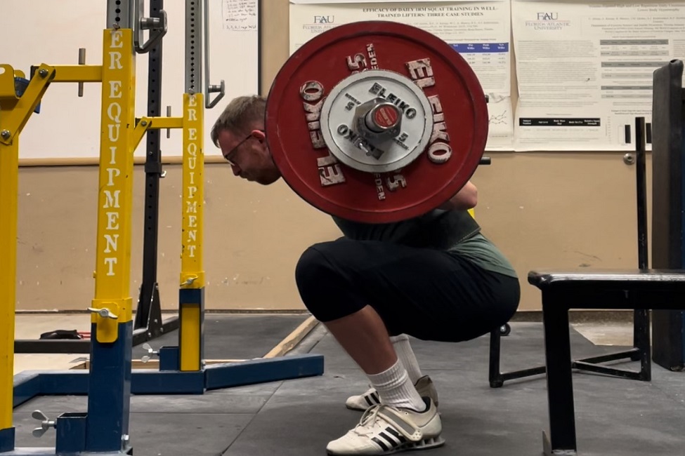 Male student performing a back squat