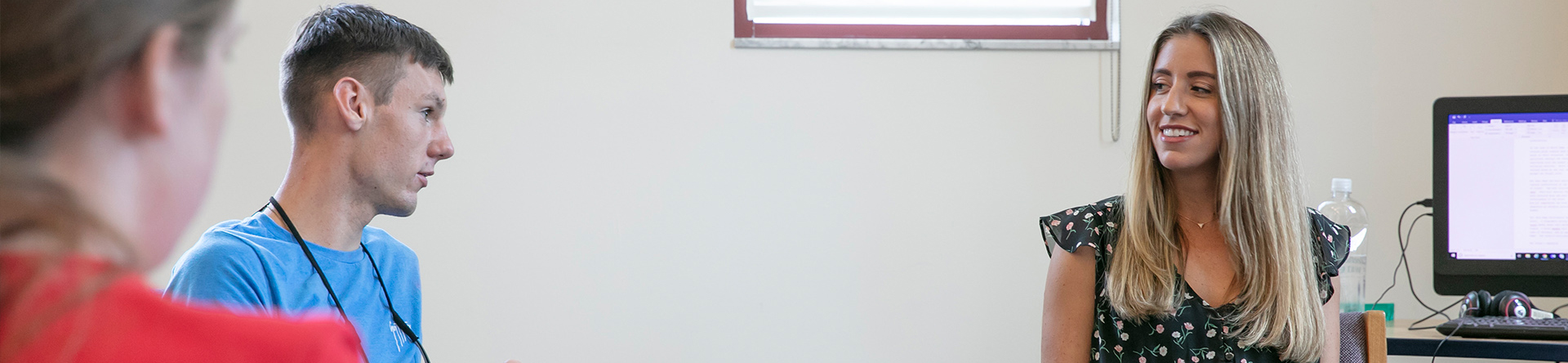 Female teacher smiling in classroom with students who are paying attention