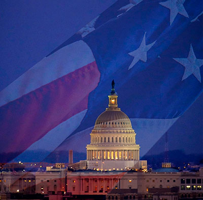 blue background with american flag and the white house lit up at night