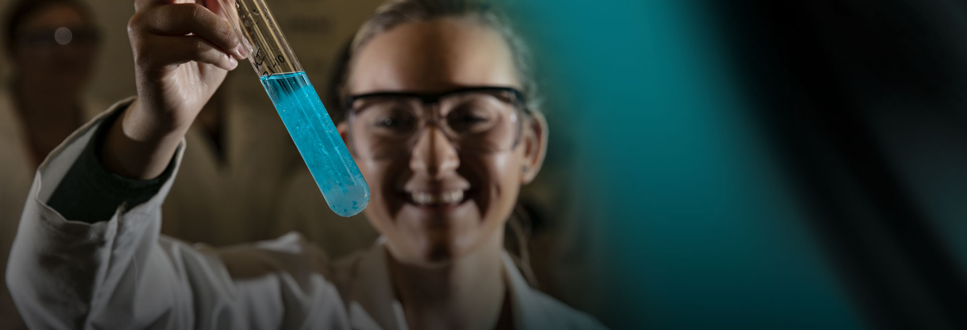 Student holding a test tube on a black and green abstract background