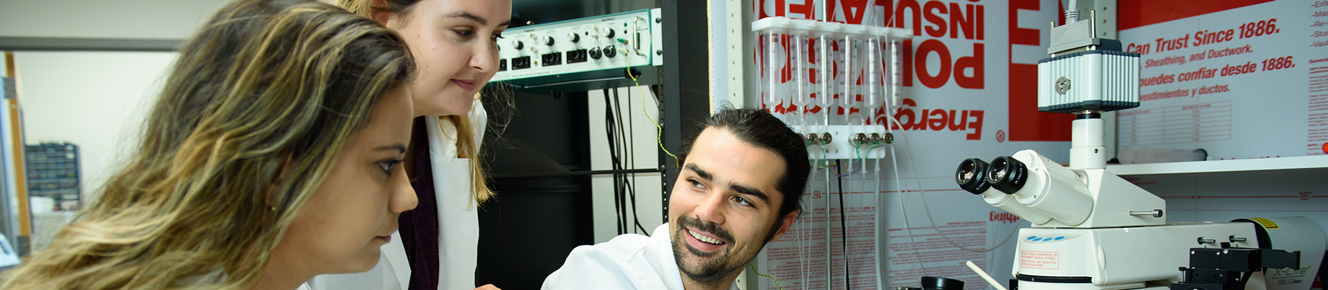 Three graduate students talking in a lab