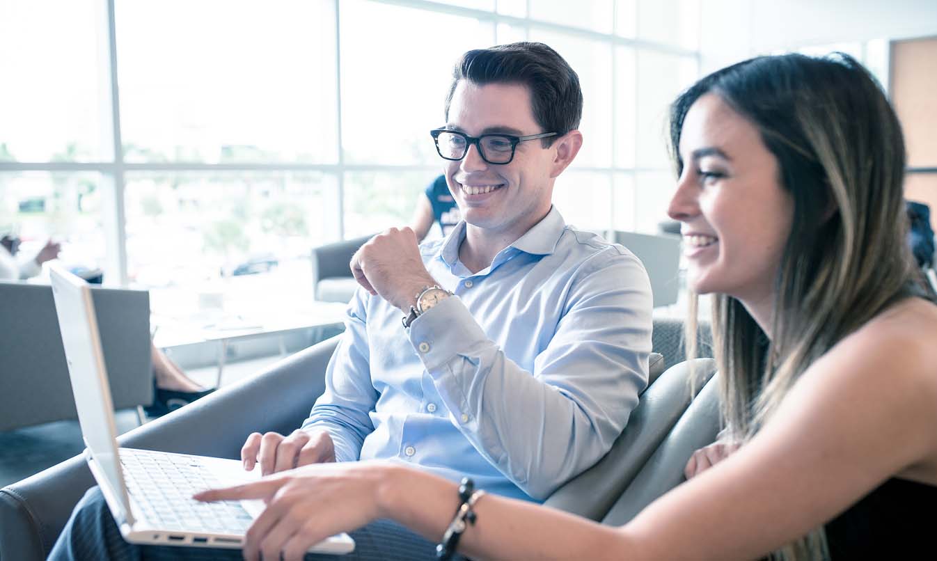 Two FAU students in front of a laptop discussing next steps after admission