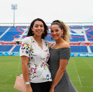 Two female alumni standingon the FAU football field