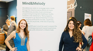 Two women standing in fromnt of a poster smiling