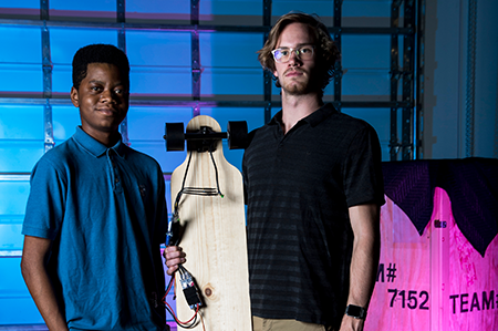 Two male students standing with skateboard