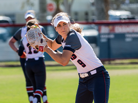 Female softball players on the field. One player is getting ready to pitch the ball.
